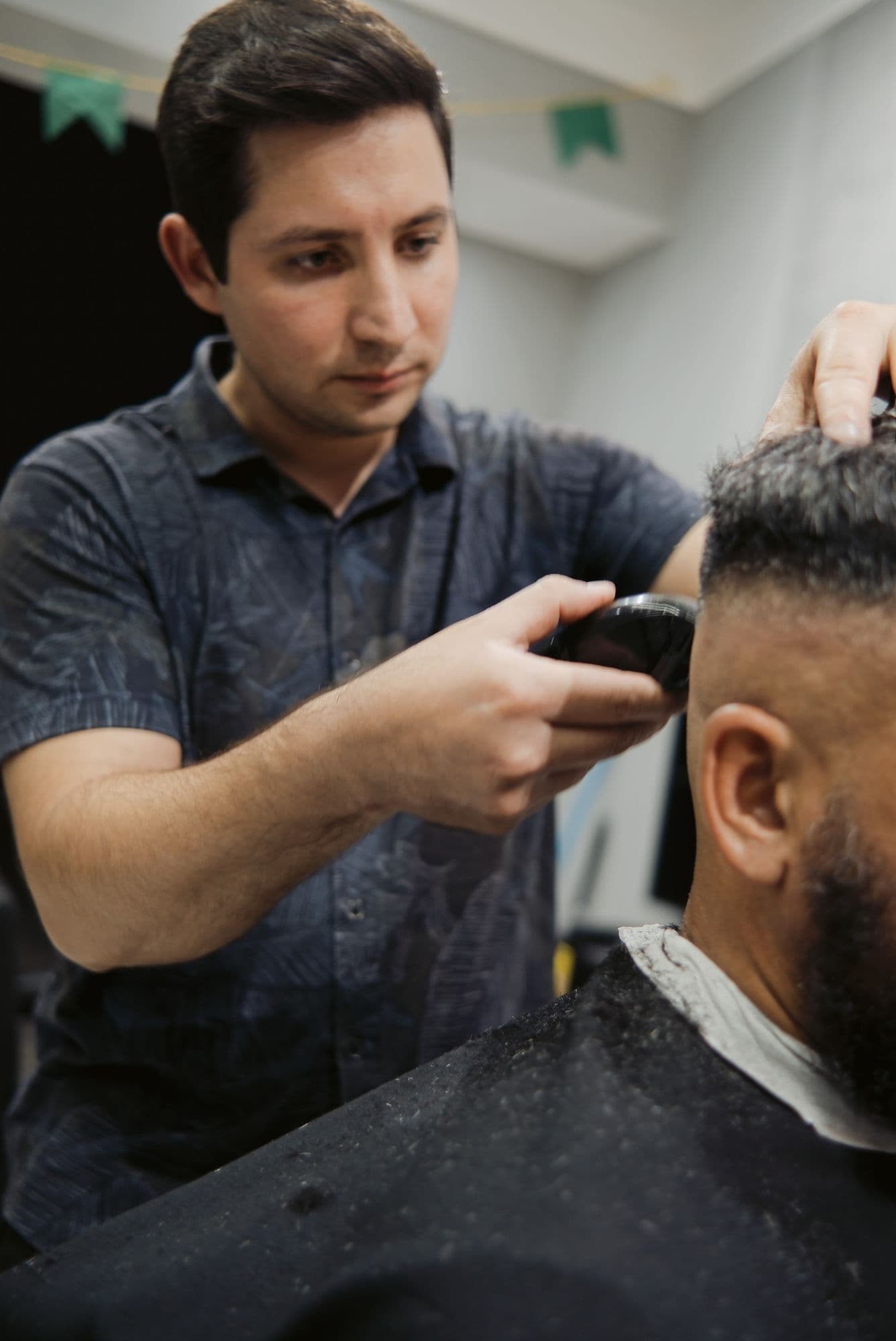 Barbeiro aparando a barba de um cliente